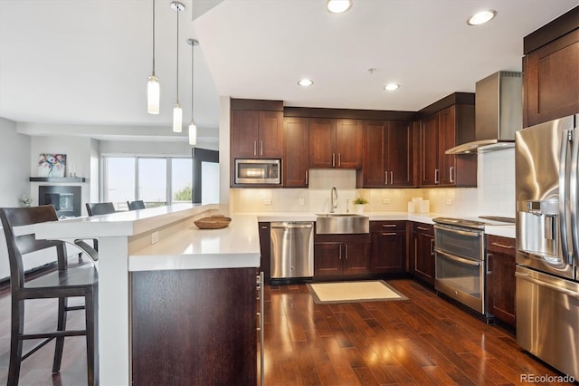 4875 S Monaco St Unit 303, Denver, CO 80237 - kitchen featuring appliances with stainless steel finishes, a sink, wall chimney range hood, light countertops, and recessed lighting