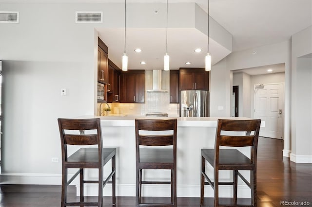 4875 S Monaco St Unit 303, Denver, CO 80237 - kitchen featuring appliances with stainless steel finishes, wall chimney exhaust hood, light countertops, a peninsula, and backsplash