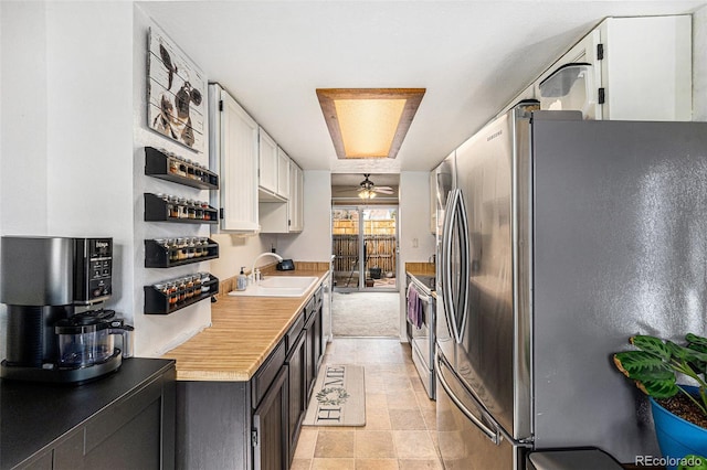 kitchen featuring a ceiling fan, a sink, stainless steel appliances, light countertops, and white cabinetry