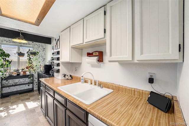 kitchen with white cabinetry, light countertops, and a sink