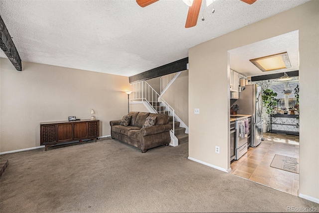 living area featuring light colored carpet, a textured ceiling, stairs, and baseboards