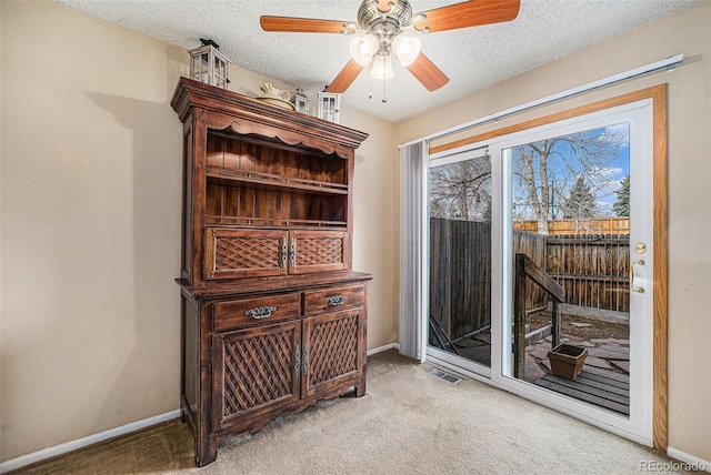 entryway featuring baseboards, light carpet, and a textured ceiling