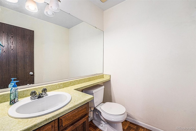 half bathroom with vanity, toilet, and baseboards