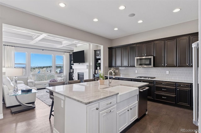 kitchen with a sink, stainless steel appliances, dark wood-style flooring, and open floor plan