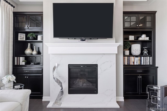 living room with dark wood-style flooring, baseboards, and a high end fireplace
