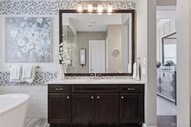 bathroom with a freestanding tub, vanity, and tile walls