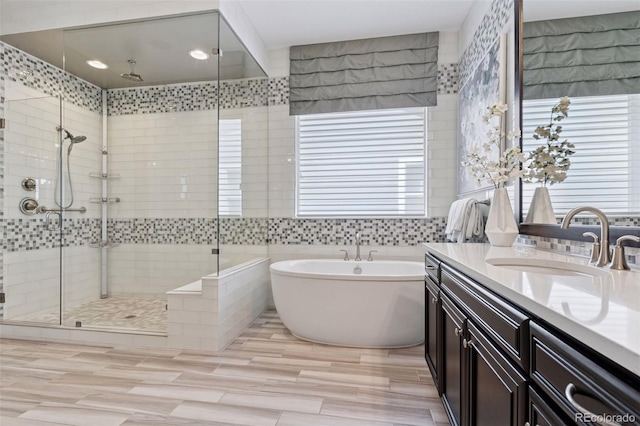 full bathroom featuring vanity, a soaking tub, tile walls, and a shower stall