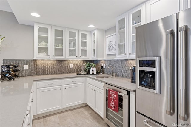 kitchen with decorative backsplash, beverage cooler, white cabinets, stainless steel fridge with ice dispenser, and a sink