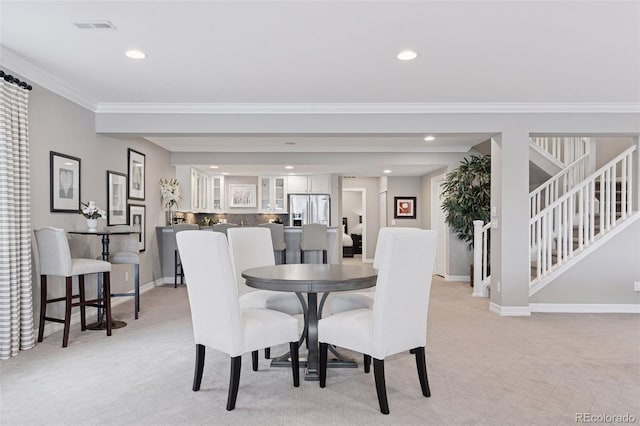 dining space featuring crown molding, baseboards, light colored carpet, and visible vents