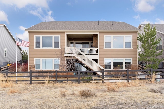 back of house with a fenced backyard and stone siding