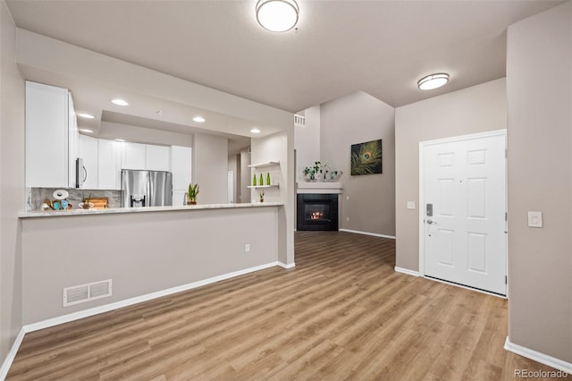 12919 W Burgundy Dr, Littleton, CO 80127 - kitchen featuring stainless steel fridge with ice dispenser, light wood-type flooring, white cabinetry, a fireplace, and recessed lighting