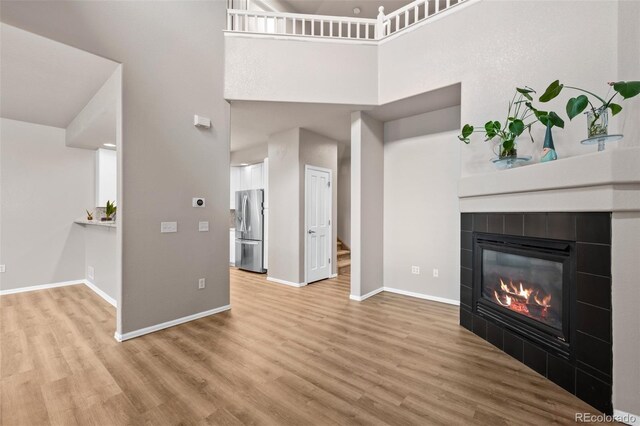 12919 W Burgundy Dr, Littleton, CO 80127 - unfurnished living room featuring wood finished floors, a tile fireplace, a high ceiling, and stairway