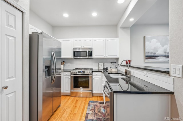 1441 S Ulster St, Denver, CO 80231 - kitchen featuring stainless steel appliances, a sink, white cabinetry, light wood-style floors, and tasteful backsplash