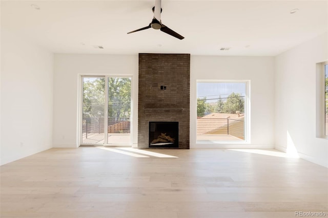 unfurnished living room featuring a fireplace, ceiling fan, and light hardwood / wood-style floors