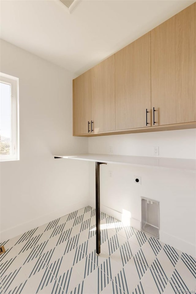 laundry area with electric dryer hookup and cabinets