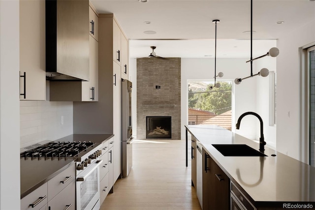 kitchen with decorative light fixtures, light wood-type flooring, stainless steel refrigerator, sink, and high end white range oven