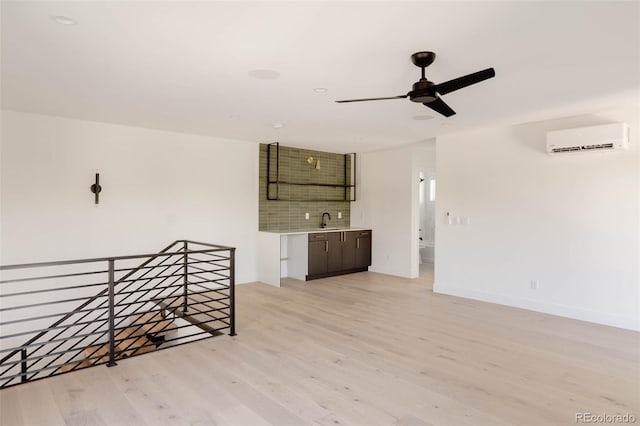 empty room featuring ceiling fan, light hardwood / wood-style floors, a wall mounted air conditioner, and sink