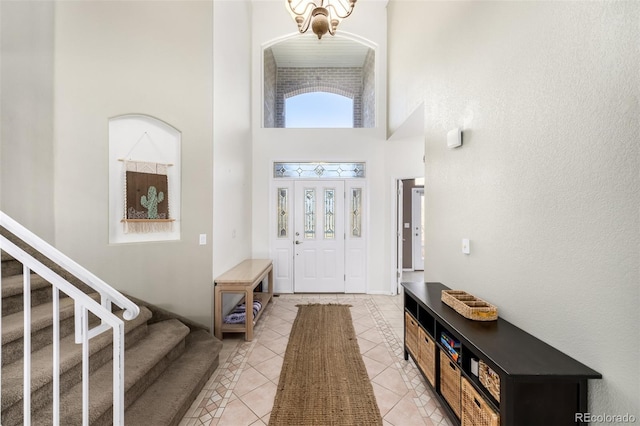 foyer entrance featuring a notable chandelier, light tile patterned floors, and a high ceiling