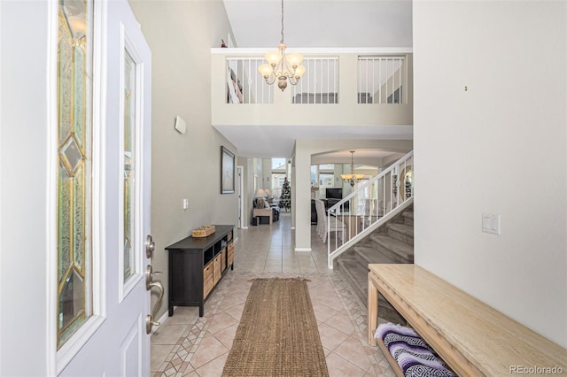 tiled entryway featuring high vaulted ceiling and a notable chandelier