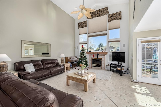 living room with a high end fireplace, ceiling fan, light tile patterned floors, and high vaulted ceiling