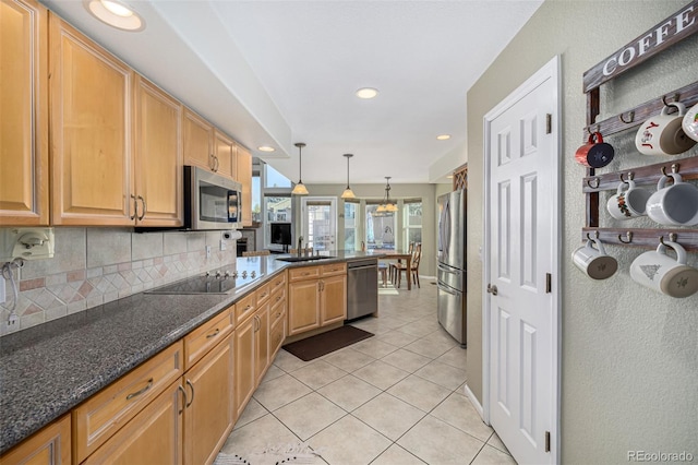 kitchen featuring sink, dark stone counters, pendant lighting, light tile patterned floors, and appliances with stainless steel finishes