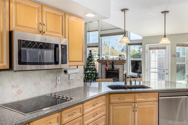 kitchen featuring plenty of natural light, sink, stainless steel appliances, and hanging light fixtures