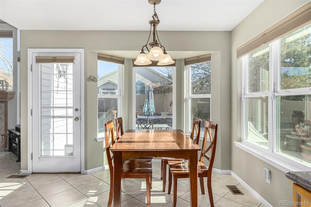 dining area with plenty of natural light, light tile patterned flooring, and a chandelier