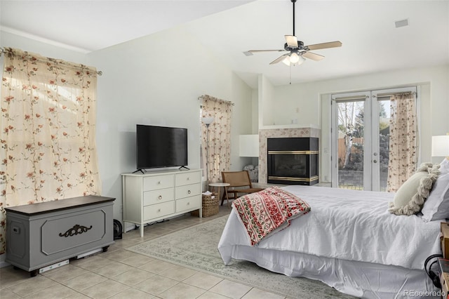 bedroom with a tile fireplace, ceiling fan, light tile patterned floors, and vaulted ceiling