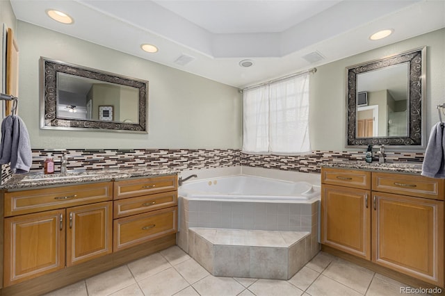 bathroom featuring decorative backsplash, vanity, tile patterned floors, and tiled tub