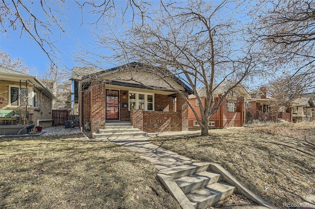 view of front of house with central AC unit, a front lawn, and brick siding