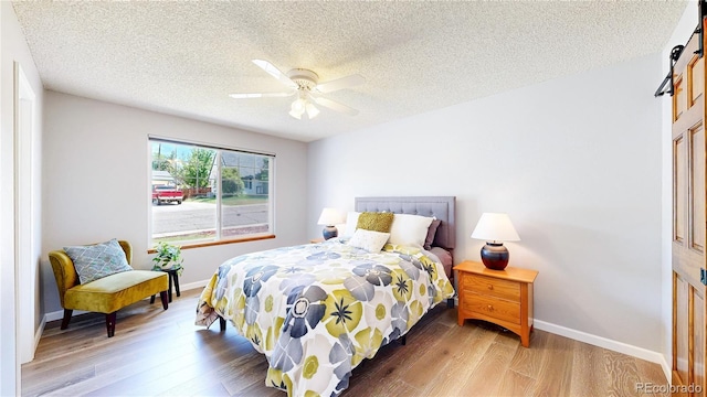 6836 W 79th Dr, Arvada, CO 80003 - bedroom with a barn door, wood finished floors, a textured ceiling, and a ceiling fan