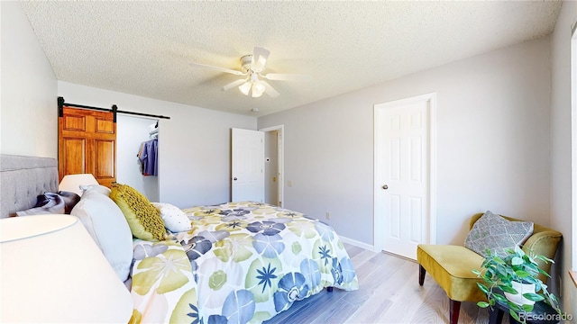 6836 W 79th Dr, Arvada, CO 80003 - bedroom with light wood-style flooring, a textured ceiling, a ceiling fan, and a barn door