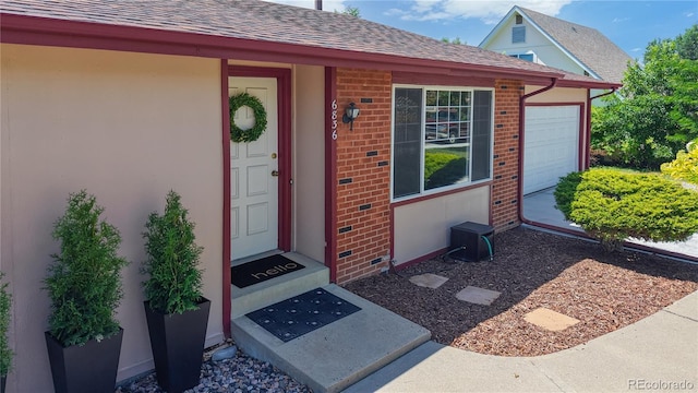 6836 W 79th Dr, Arvada, CO 80003 - view of exterior entry featuring brick siding, roof with shingles, and an attached garage