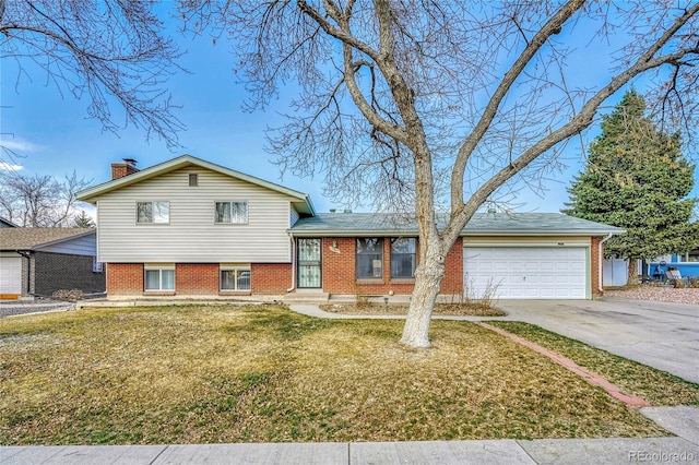 tri-level home with concrete driveway, a front yard, an attached garage, brick siding, and a chimney