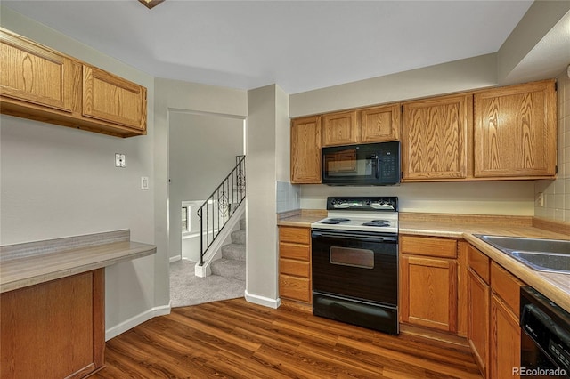 kitchen featuring a sink, dark wood-type flooring, black appliances, and light countertops