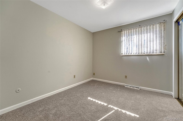 carpeted spare room with visible vents and baseboards