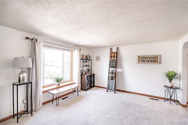 sitting room with baseboards, carpet floors, arched walkways, and visible vents