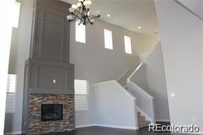 15305 W 93rd Ave, Arvada, CO 80007 - unfurnished living room with a chandelier, stairs, and a stone fireplace