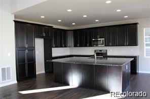 15305 W 93rd Ave, Arvada, CO 80007 - kitchen featuring stainless steel microwave, dark wood-style flooring, a center island with sink, baseboards, and recessed lighting