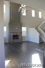 15305 W 93rd Ave, Arvada, CO 80007 - unfurnished living room with a chandelier, a fireplace, dark wood finished floors, and baseboards