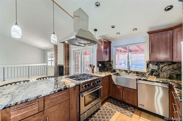 kitchen featuring lofted ceiling, appliances with stainless steel finishes, island exhaust hood, stone counters, and a sink