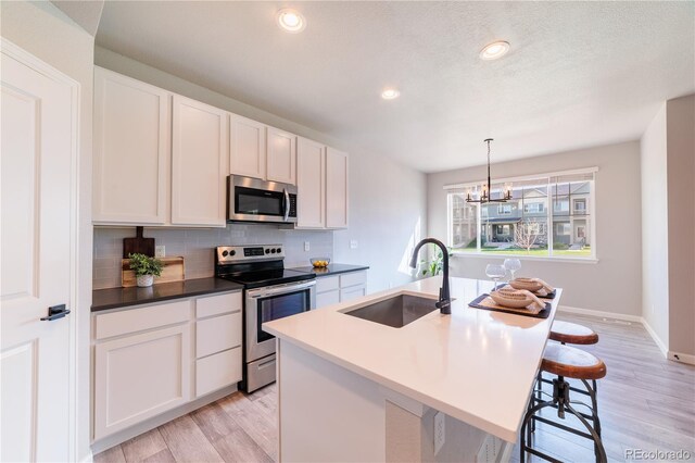 2640 Brookstone Dr Unit B, Milliken, CO 80543 - kitchen featuring appliances with stainless steel finishes, backsplash, light wood-style floors, a chandelier, and recessed lighting