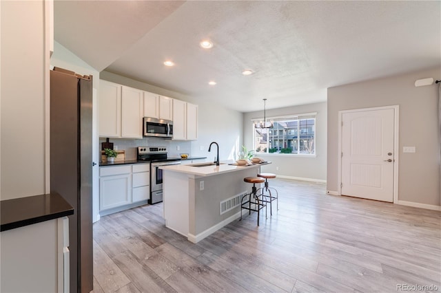 2640 Brookstone Dr Unit B, Milliken, CO 80543 - kitchen with appliances with stainless steel finishes, a breakfast bar area, recessed lighting, an island with sink, and light wood finished floors