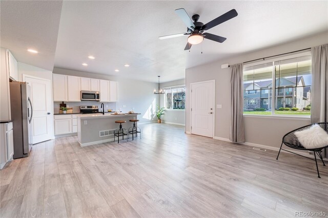 2640 Brookstone Dr Unit B, Milliken, CO 80543 - kitchen featuring appliances with stainless steel finishes, a kitchen bar, recessed lighting, light wood-type flooring, and white cabinetry