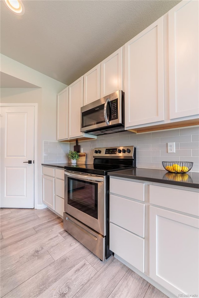 2640 Brookstone Dr Unit B, Milliken, CO 80543 - kitchen featuring appliances with stainless steel finishes, dark countertops, light wood finished floors, and backsplash