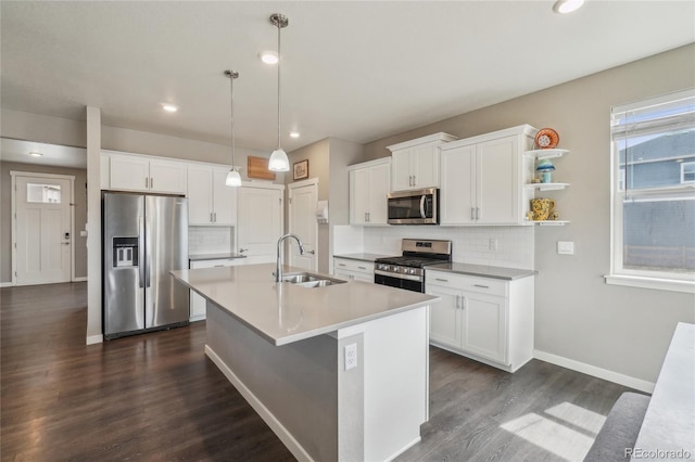 kitchen with dark wood-type flooring, decorative backsplash, a sink, a kitchen island with sink, and appliances with stainless steel finishes