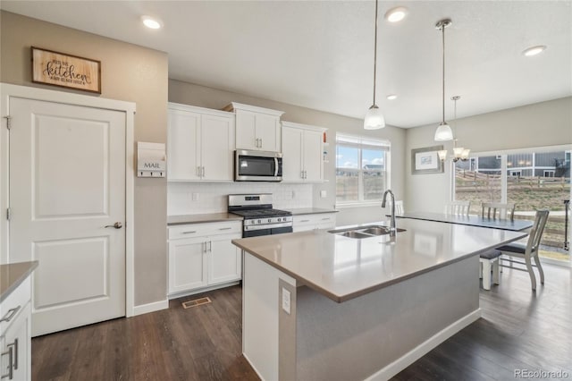 kitchen featuring a sink, dark wood-type flooring, backsplash, white cabinets, and appliances with stainless steel finishes