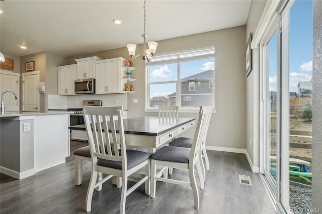 dining area featuring baseboards, dark wood-style floors, a notable chandelier, and plenty of natural light