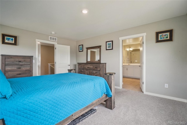 carpeted bedroom with connected bathroom, visible vents, and baseboards