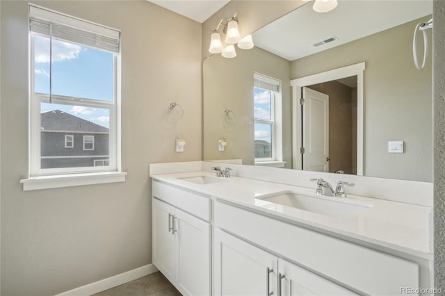 bathroom featuring double vanity, visible vents, baseboards, and a sink